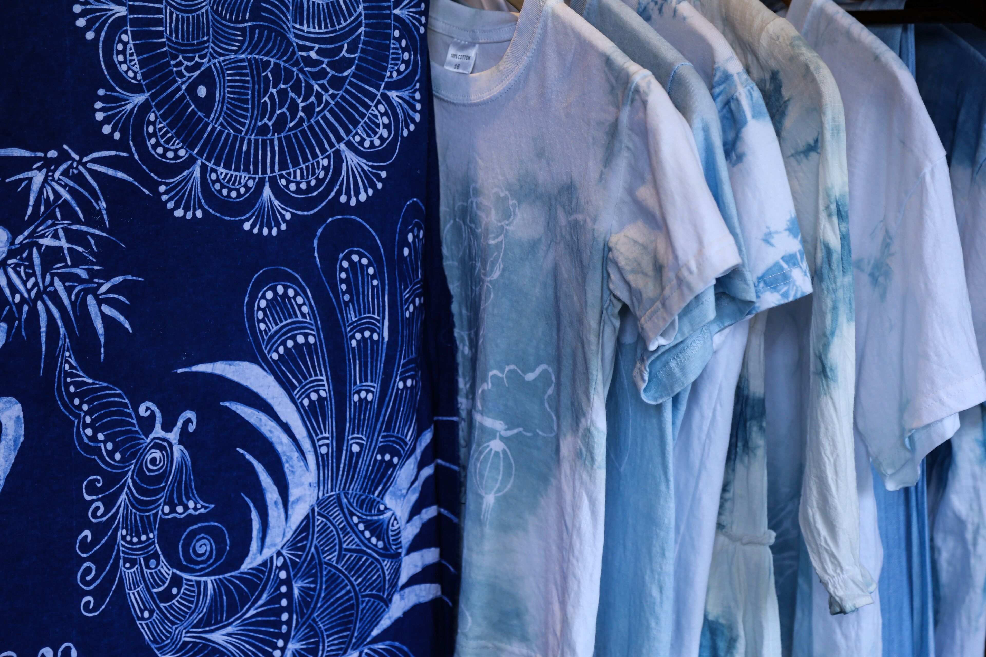 Een rek met t-shirts met verschillende designs, waaronder een opvallend blauw-wit patroon.