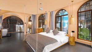 Un'ampia camera da letto con un letto grande, un comodino in legno e vista sull'esterno attraverso finestre ad arco.