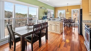 Une cuisine spacieuse avec un plancher en bois, de grandes fenêtres et une vue sur l’extérieur.