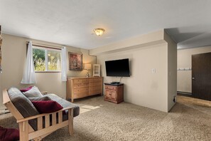 A room with a wooden sofa, a TV, a cabinet, and a window with curtains.