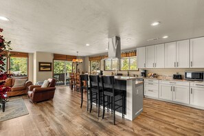A spacious kitchen with a central island, white cabinets, and a dining area with a brown leather sofa and chairs.