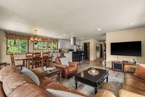 A spacious living room with a leather sofa, a coffee table, and a television. - Leavenworth Retreat with Pool & Hot Tub (Leavenworth)
