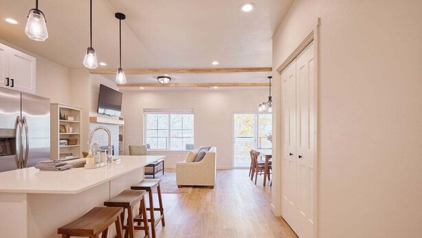 A modern kitchen with a central island, wooden stools, and pendant lighting. - 2BR/2BA Riverfront Condo w/ Deck (Cashmere)
