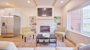 A modern living room with a fireplace, a flat-screen TV, and a large window. - 2BR/2BA Riverfront Condo w/ Deck (Cashmere)