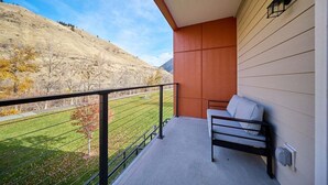 A balcony with a view of a grassy field and a hill. - 2BR/2BA Riverfront Condo w/ Deck (Cashmere)