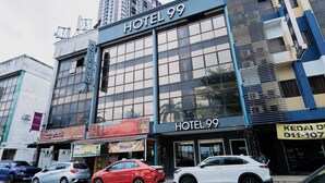 Ein Hotel mit einer großen Beschilderung mit der Aufschrift 'HOTEL 99', mehreren Fenstern und einem gut sichtbaren Eingang.