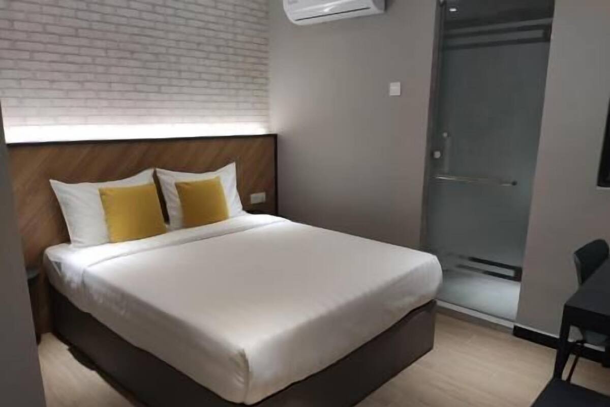 Een hotelkamer met een bed, een douche en een klein tafeltje.