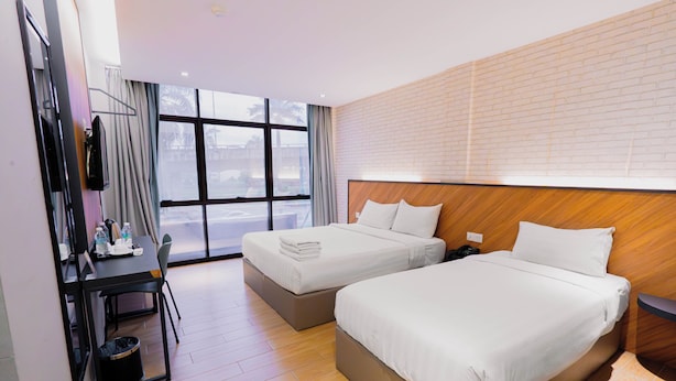 Ein Hotelzimmer mit zwei Betten, einem Schreibtisch, einem Stuhl und einem großen Fenster.