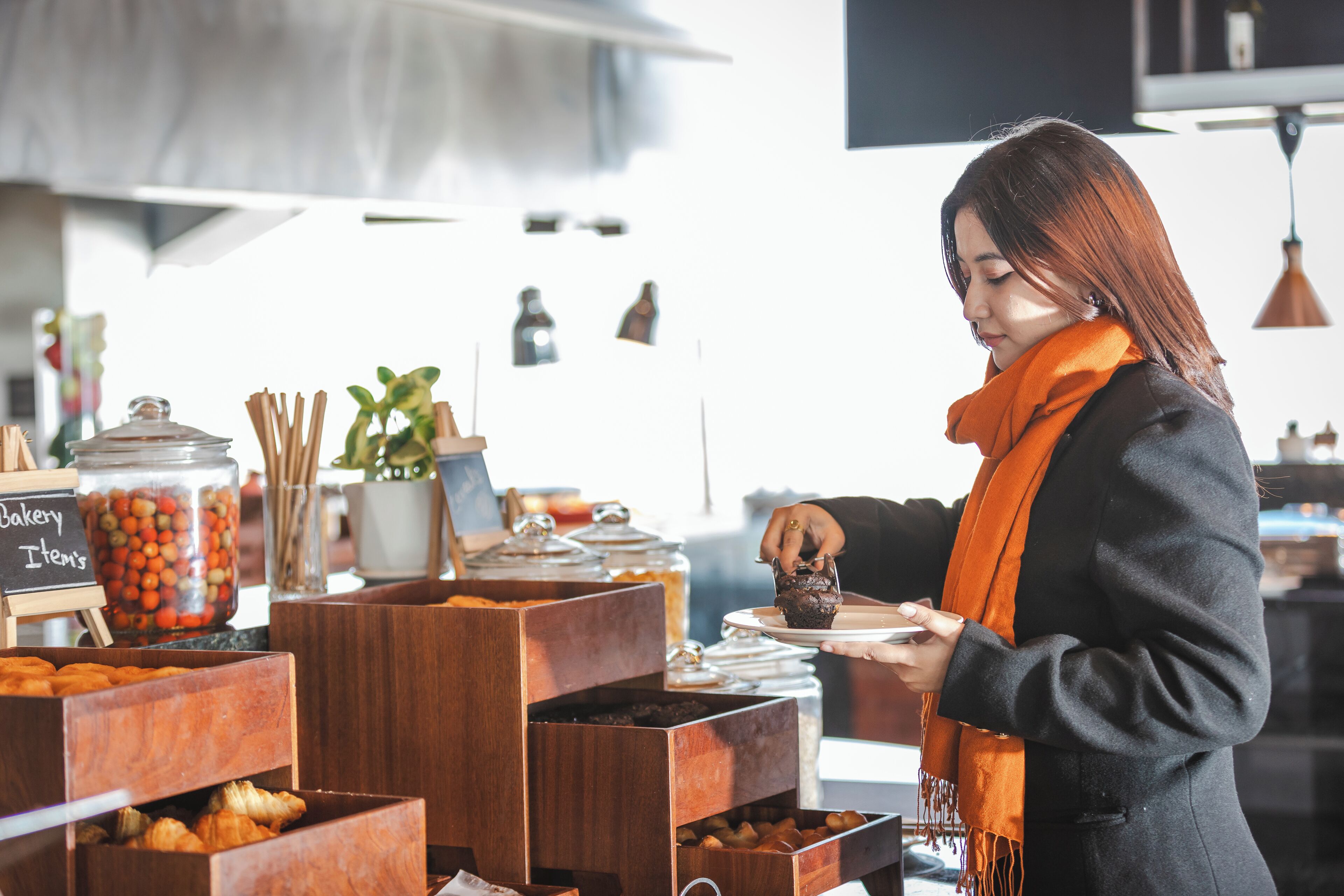 Eine Person bedient Essen von einem Buffet mit verschiedenen Speisen und Behältern.