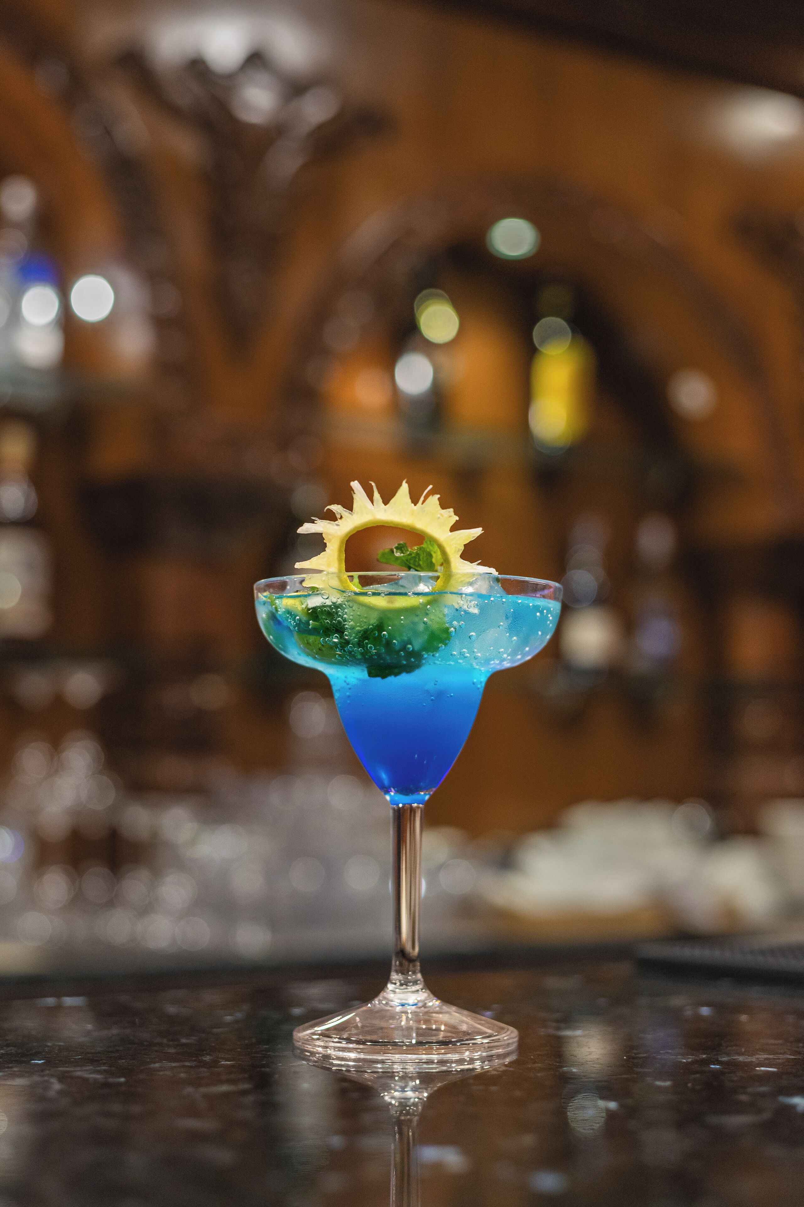 A cocktail with a decorative garnish in a glass on a bar counter.