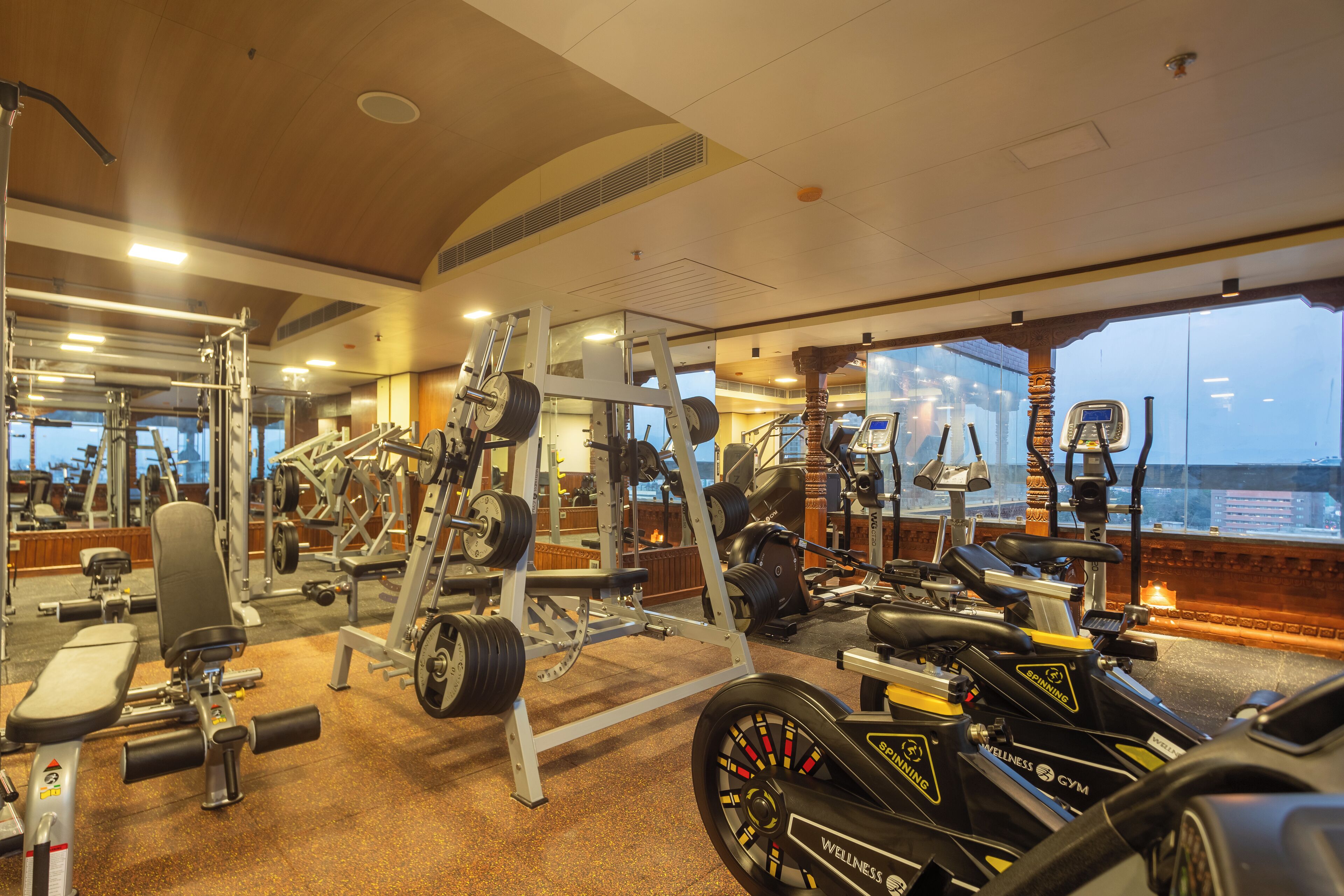 A gym with various exercise equipment, large windows, and a view of the city.