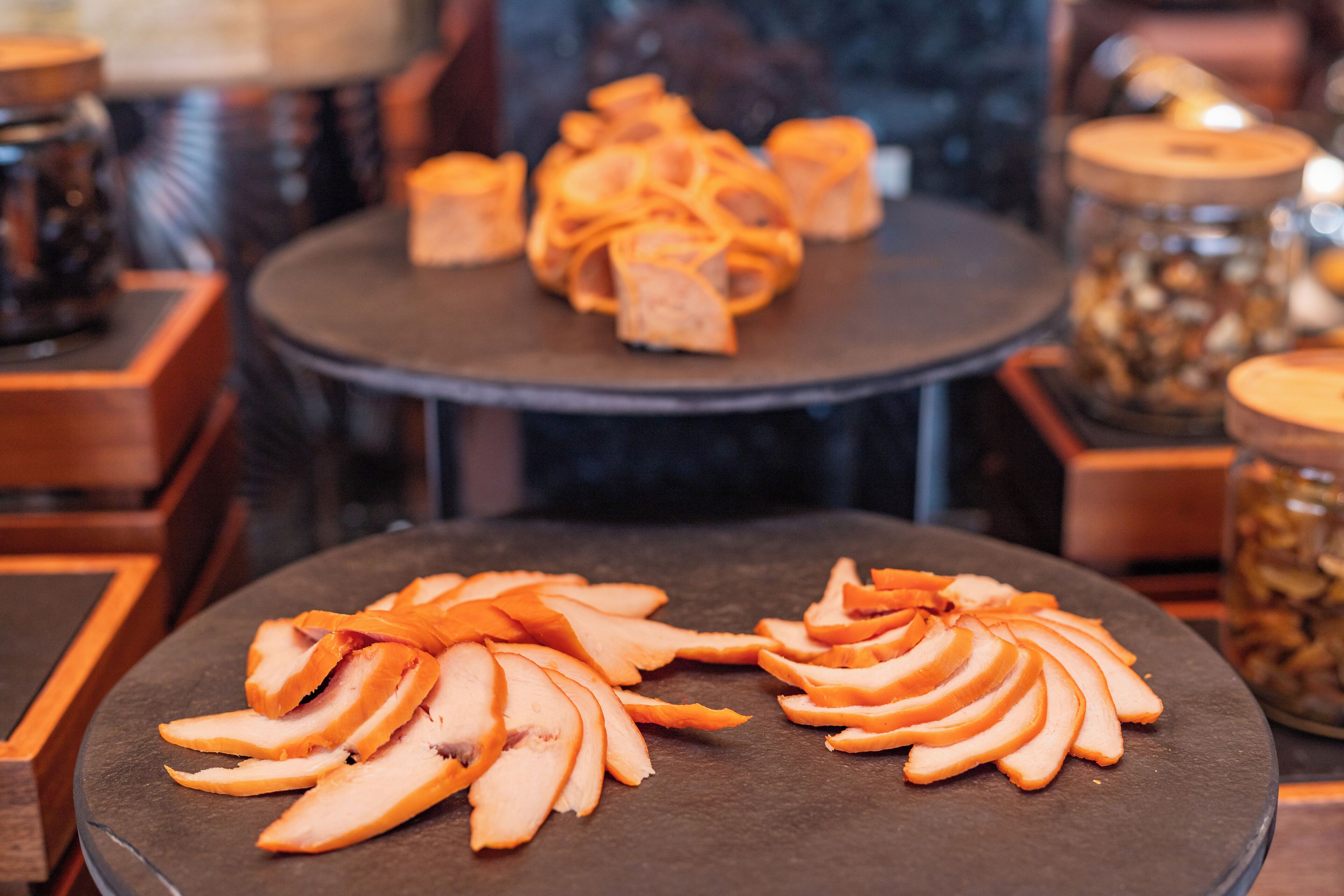 A table with sliced fruits and a jar of nuts.