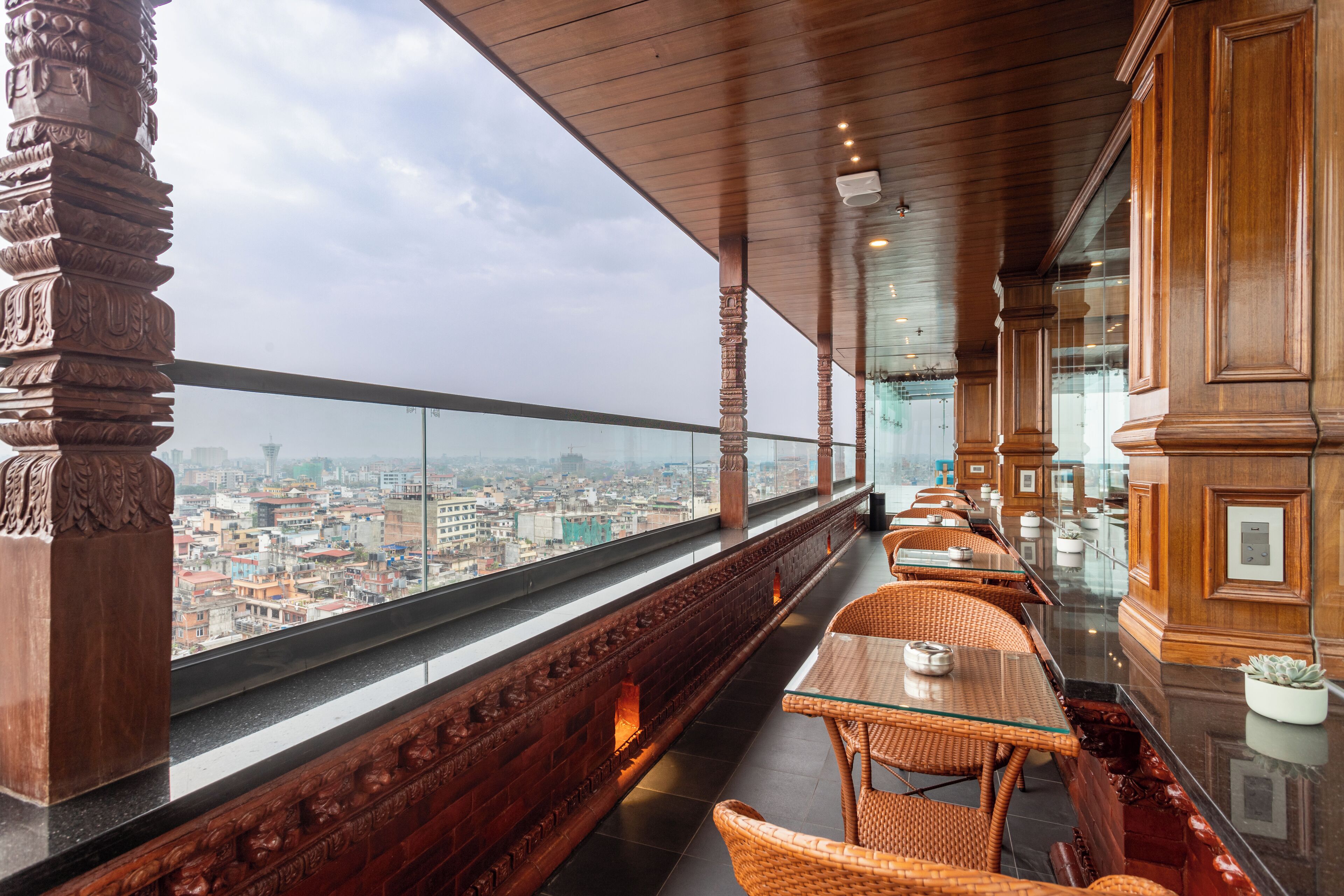 A balcony with wicker furniture, a glass railing, and a city view.