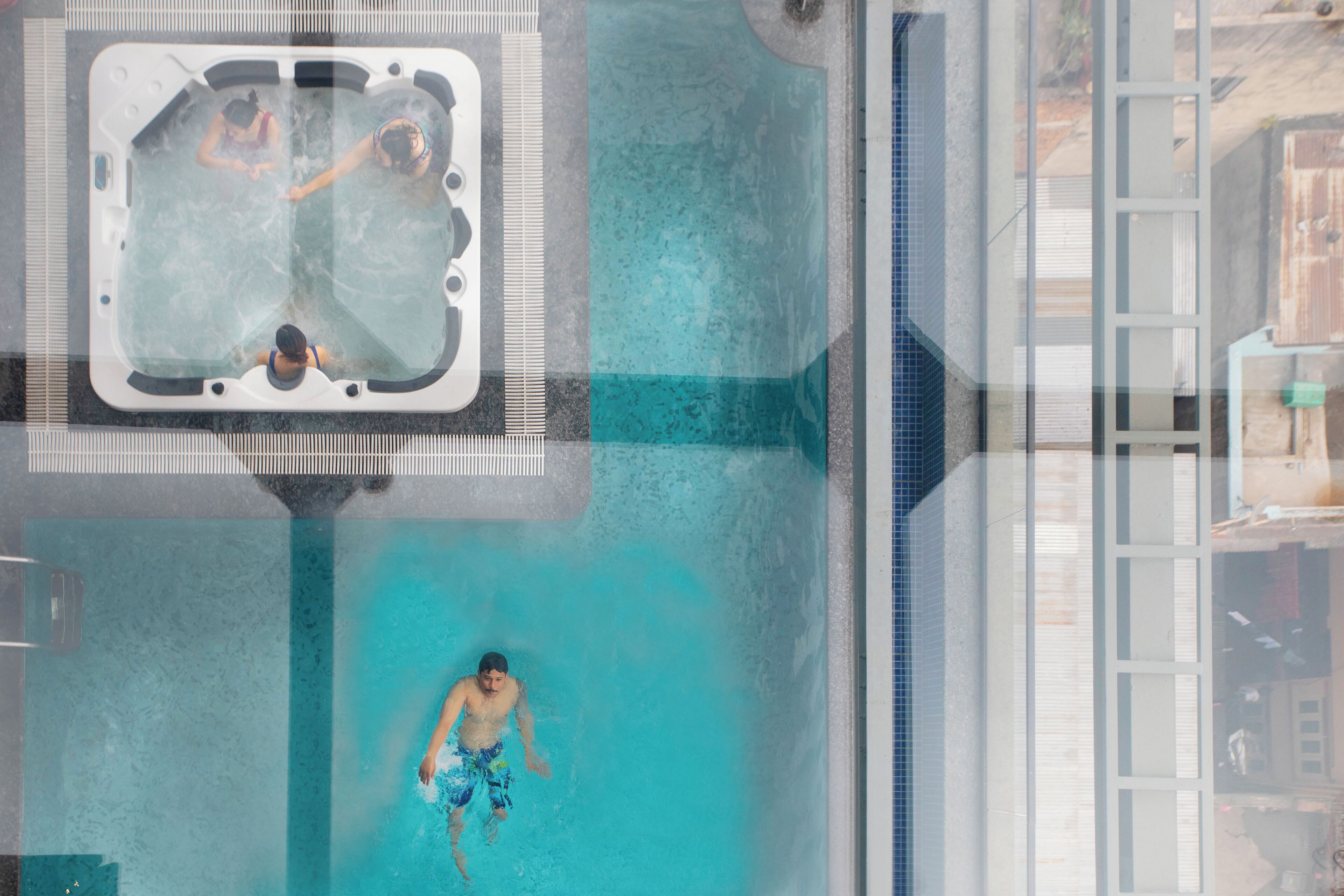 A swimming pool with a hot tub and a person swimming.