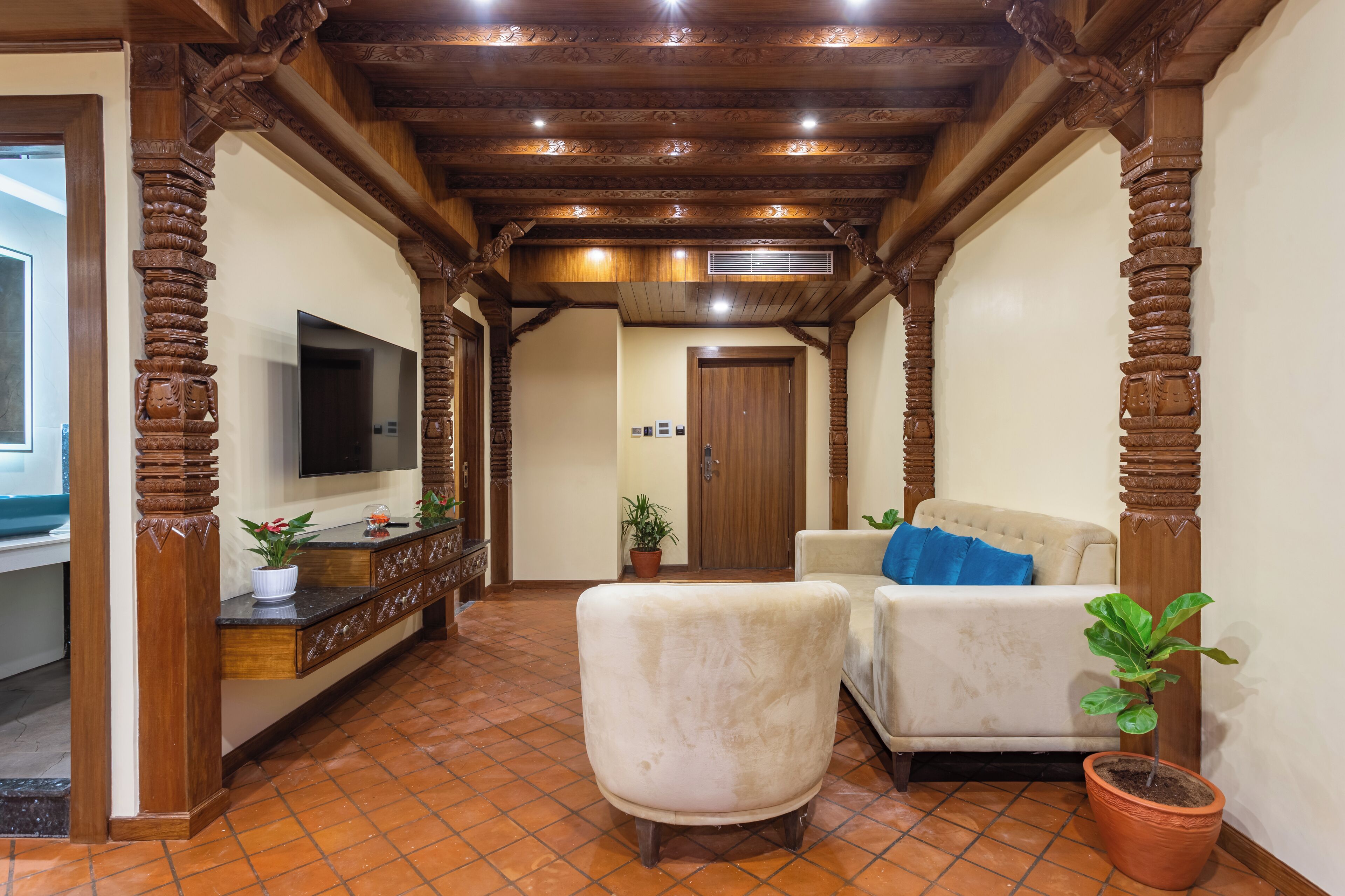 A hallway with wooden pillars, a sofa, a chair, and a television.