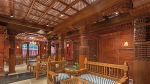 Un intérieur en bois richement décoré, avec des colonnes sculptées, un banc et une table.