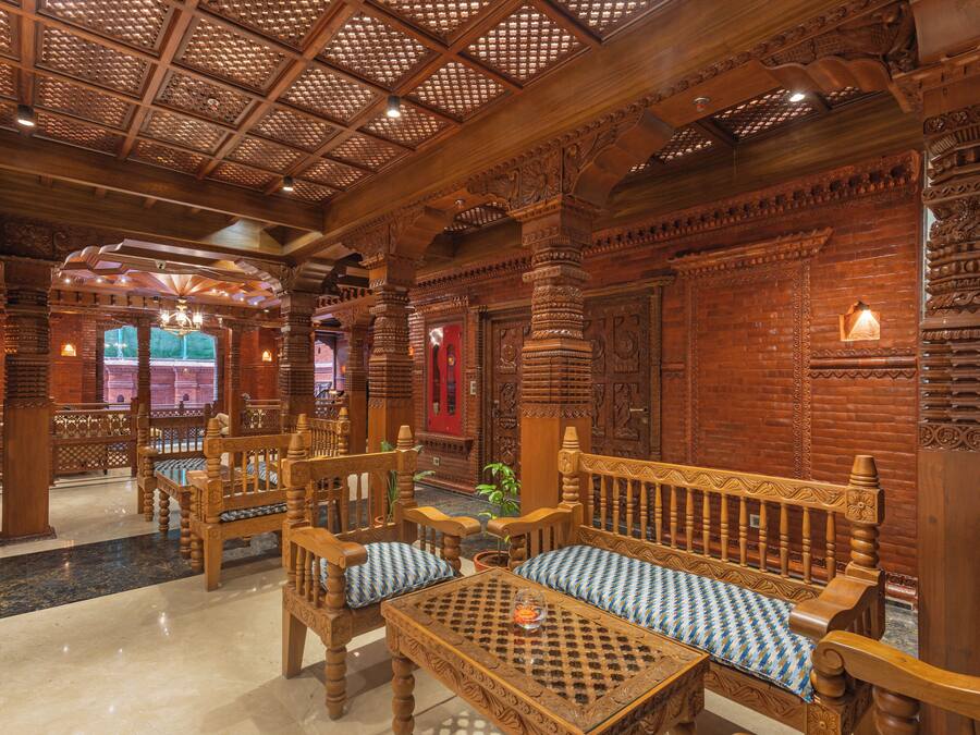 Un interior de madera ornamentado con columnas talladas, un banco y una mesa.