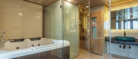 A modern bathroom with a glass-enclosed shower, a large bathtub, and a sink with a green basin.