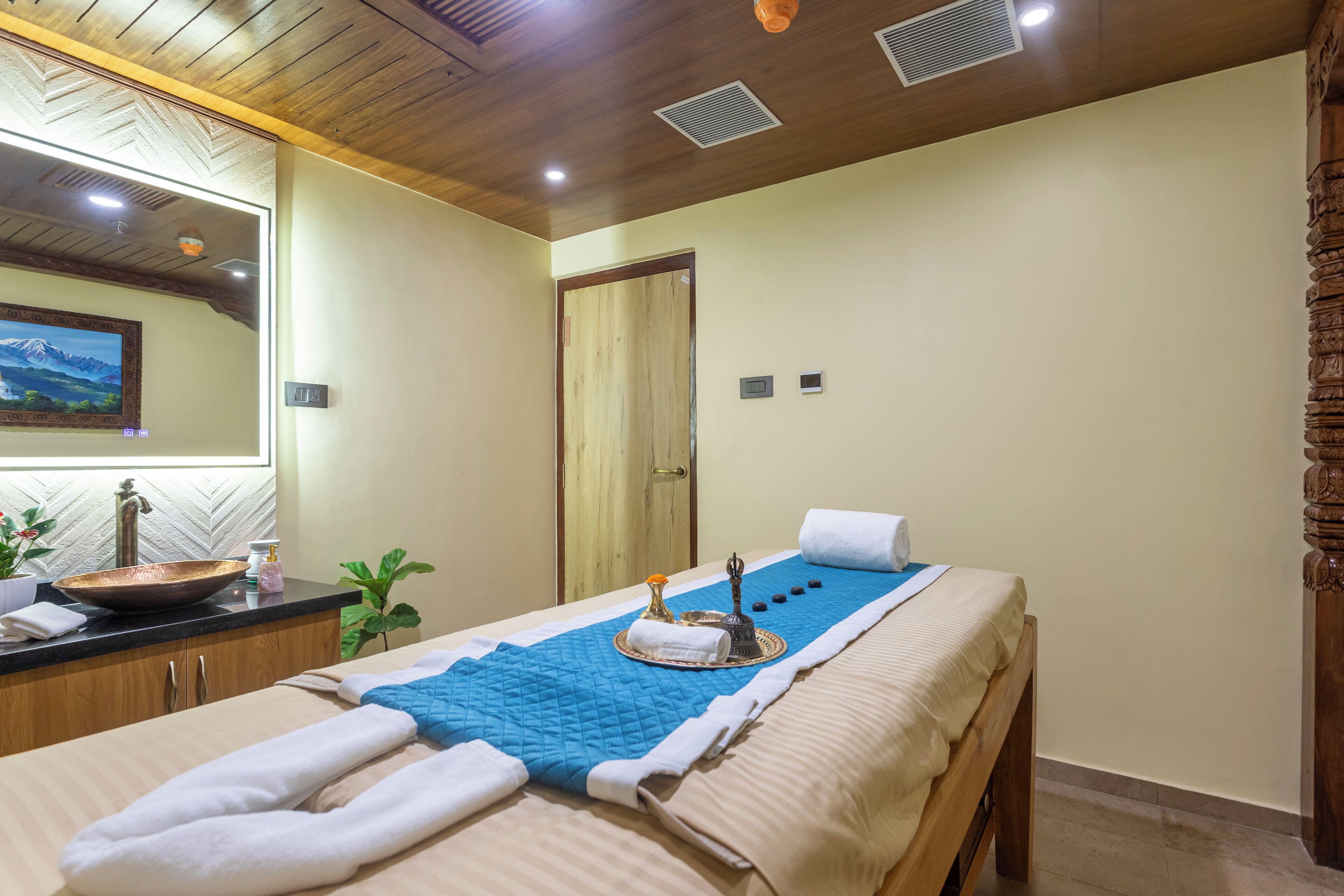 Sala de spa com mesa de massagem, toalhas, pia e espelho.