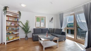 A modern living room with a sofa, a coffee table, a bookshelf, and a potted plant.