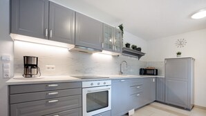 A modern kitchen with grey cabinets, a built-in oven, a microwave, and a coffee maker.