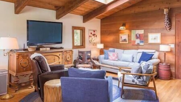 Una sala de estar acogedora con techo de madera, televisor, sofá y una mesita de centro.