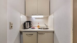 A compact kitchenette with a sink, a coffee maker, a kettle, and a dish soap bottle. - Apartment 'Ferienwohnung 7c' with Shared Terrace and Wi-Fi (Bad Bellingen)