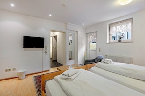 Habitación de hotel con dos camas, un televisor, una ventana con vistas y la puerta del baño.