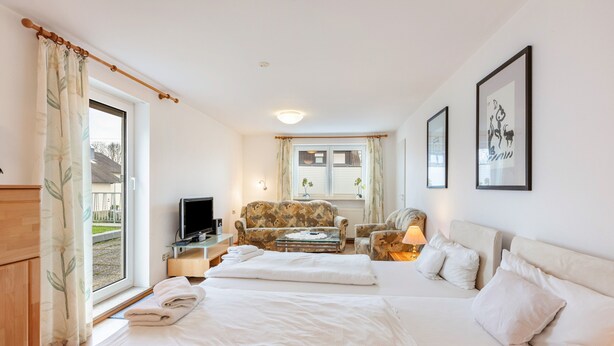 Habitación de hotel con dos camas, un sofá, un televisor y una ventana con cortinas.