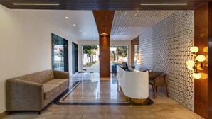 A modern lobby with a reception desk, a sofa, and a patterned wall. - Redolence Aravali Tree (Udaipur)