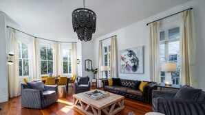 A spacious living room with hardwood flooring, a large wooden coffee table, and multiple seating options including sofas and armchairs.