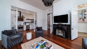 A living room with a fireplace, a television, and a kitchen in the background.