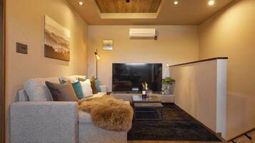 A modern living room with a sofa, a coffee table, a flat-screen TV, and a ceiling light.