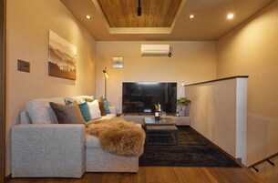 A modern living room with a sofa, a coffee table, a flat-screen TV, and a ceiling light.