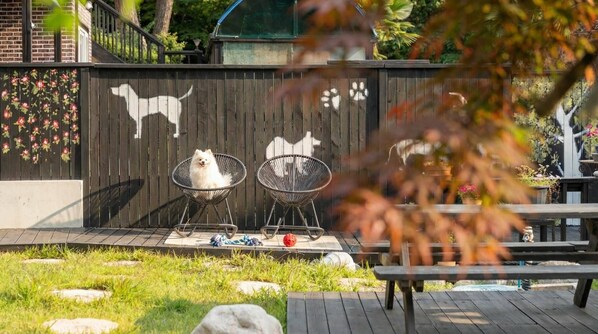 A wooden deck with two metal chairs, a picnic table, and a decorative fence with animal silhouettes. - Geoje Yeoul Pet-friendly Pension (Geoje)