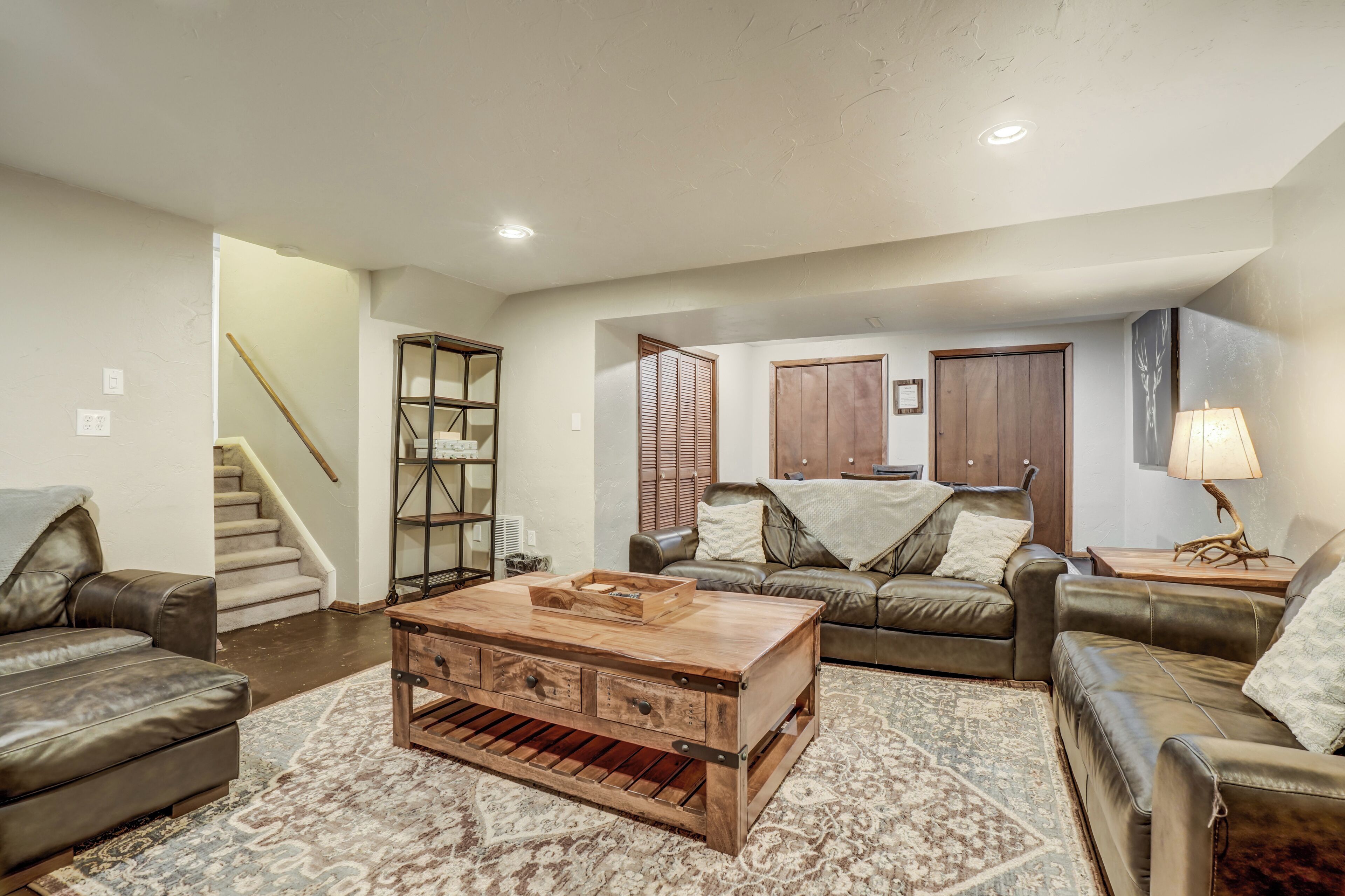 A living room with a wooden coffee table, leather sofas, a staircase, and a wooden cabinet.