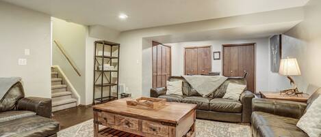 A living room with a wooden coffee table, leather sofas, a staircase, and a wooden cabinet.