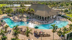 Un resort con una amplia piscina, zonas de descanso y un pabellón cubierto.