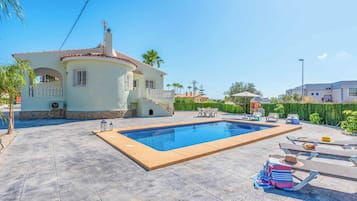 A house with a swimming pool, outdoor furniture, and a well-maintained garden.