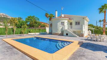 A swimming pool with a white house in the background.