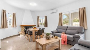 Een moderne woonkamer met een grijze bank, een houten eettafel en stoelen.