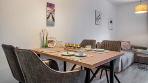 A dining area with a wooden table, chairs, and a sofa. - Apartment 'Fewo Seehase ' with Balcony and Wi-Fi (Wurster Nordseeküste)