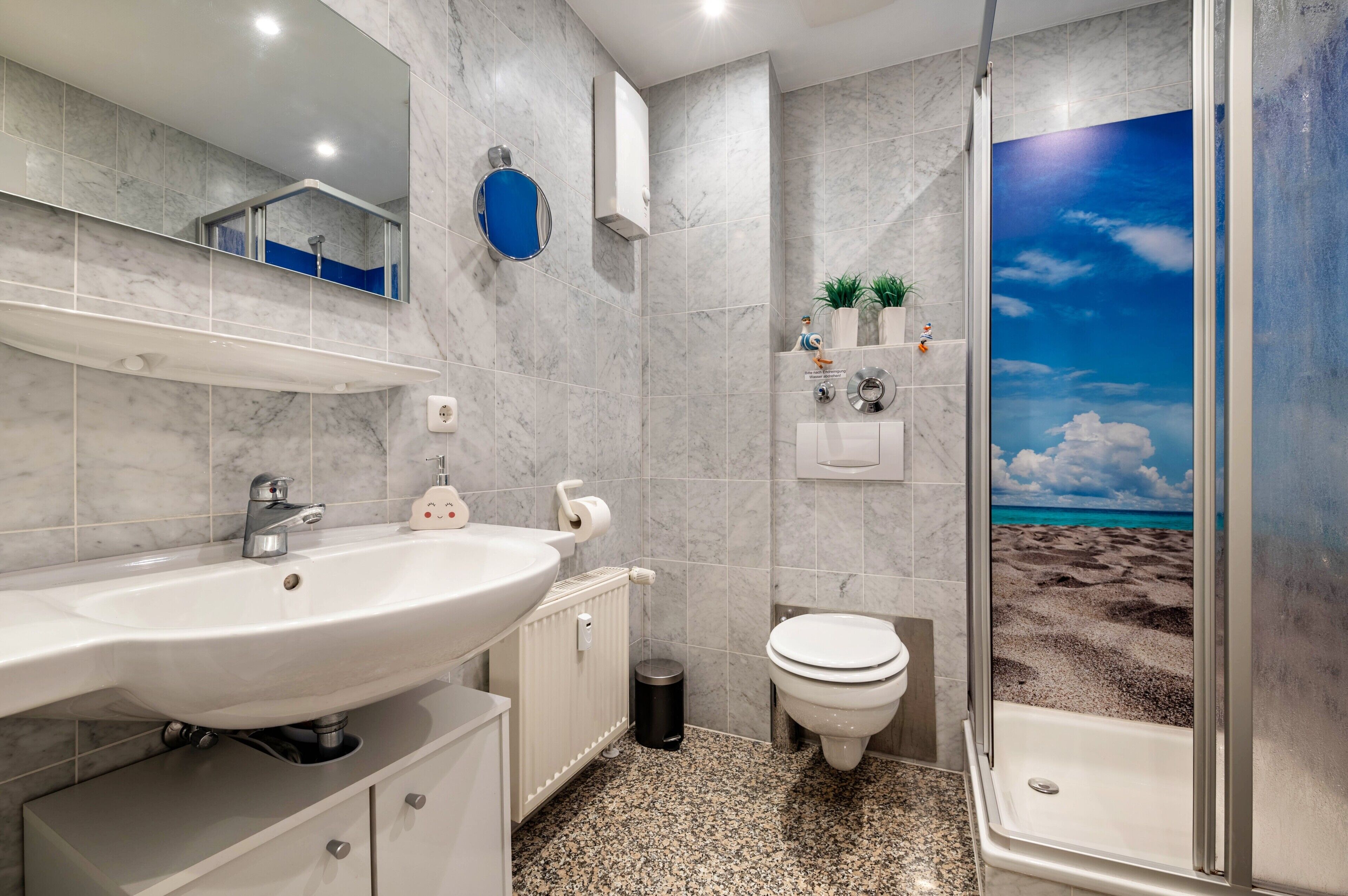 A bathroom with a large sink, toilet, and shower.