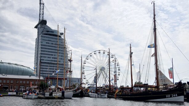A waterfront with a tall building, a Ferris wheel, and several boats. - Apartment 'Fewo Seehase ' with Balcony and Wi-Fi (Wurster Nordseeküste)