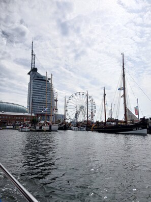 Een waterkant met een hoog gebouw, een reuzenrad en verschillende boten.
