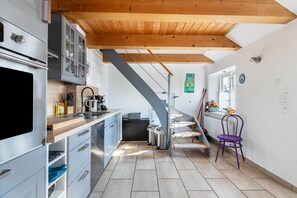 Una cocina moderna con techo de madera, una escalera y una silla morada.