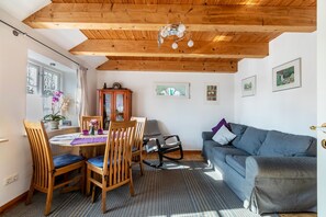 Una habitación con techo de madera, una mesa de comedor con sillas, un sofá y cuadros en la pared.