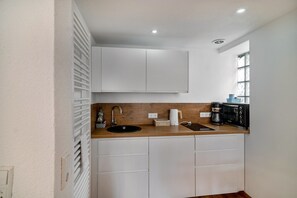 A compact kitchen with a sink, a coffee maker, and a microwave.