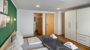 Ein Hotelzimmer mit einem Bett, einem Kleiderschrank, einem durchgegangenes Badezimmer und Kunstwerken an der Wand.