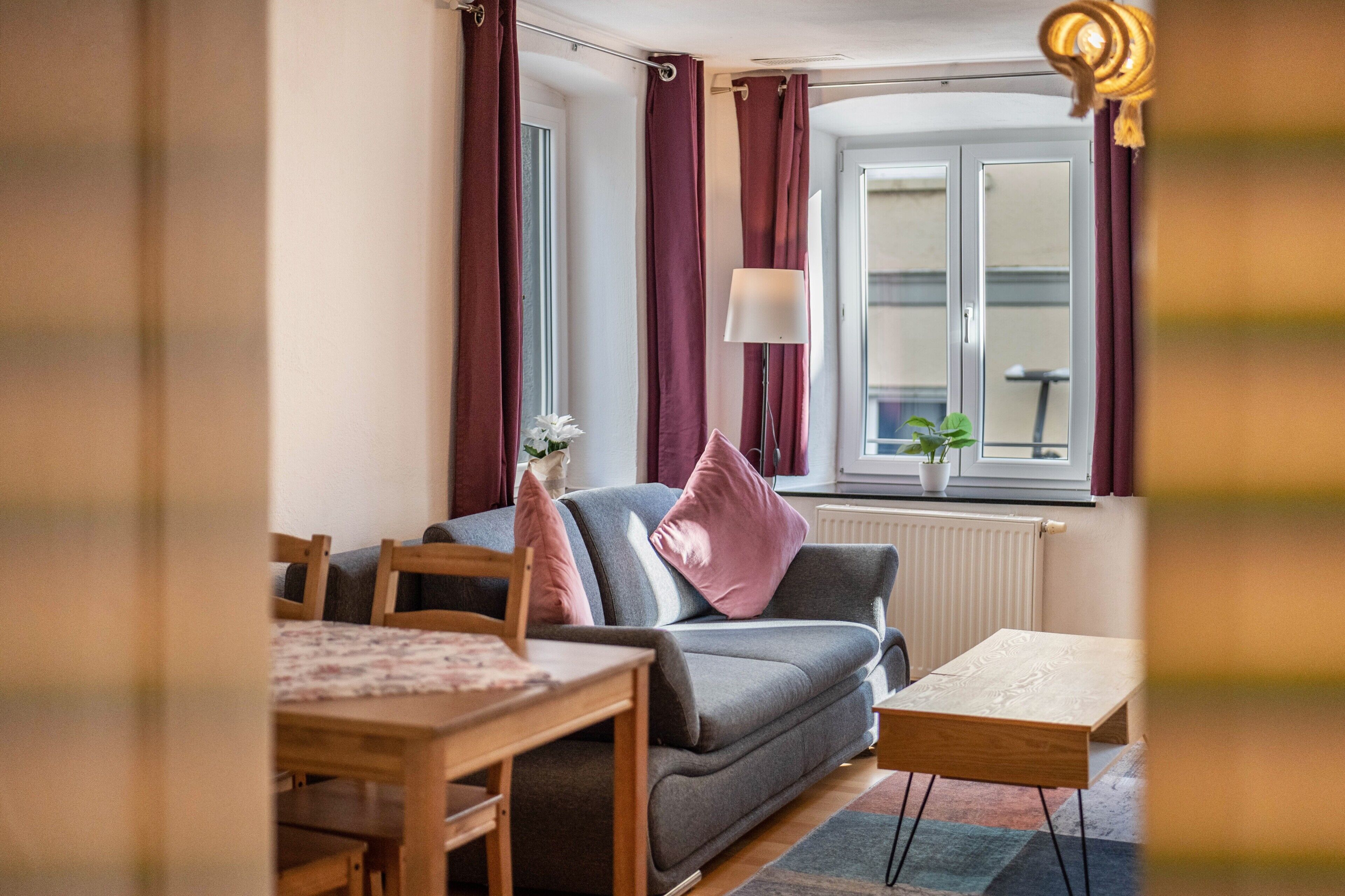 Un salon avec un canapé, une table et une fenêtre avec des rideaux.